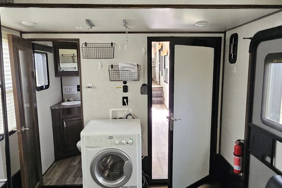 RV rental interior showcasing a washer/dryer, dual TVs, bathroom, and tie-down points on the durable floor.