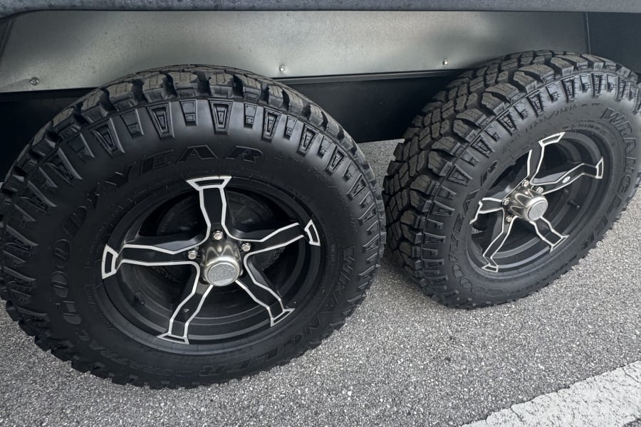 Two sturdy Goodyear Wrangler off-road tires with black rims are seen on an RV rental.