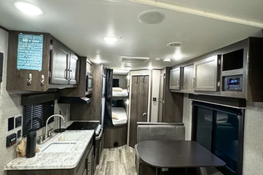 Spacious RV rental interior with kitchen, dining area, and bunk beds. Perfect for your next camping trip.