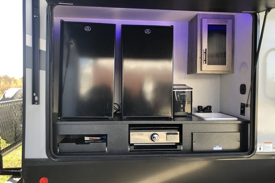 Convenient rv rental outdoor kitchen with two fridges, sink, Greystone grill, and coffee maker.