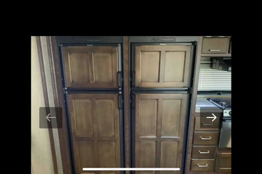 RV rental kitchen: two Dometic refrigerators with wood-paneled doors, integrated into a functional interior with stove and drawers.