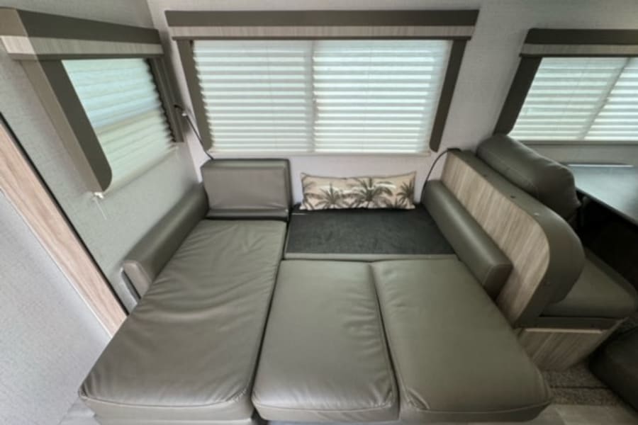 RV rental: Gray convertible sofa cushions extended to form a bed, maximizing space in this modern camper interior.