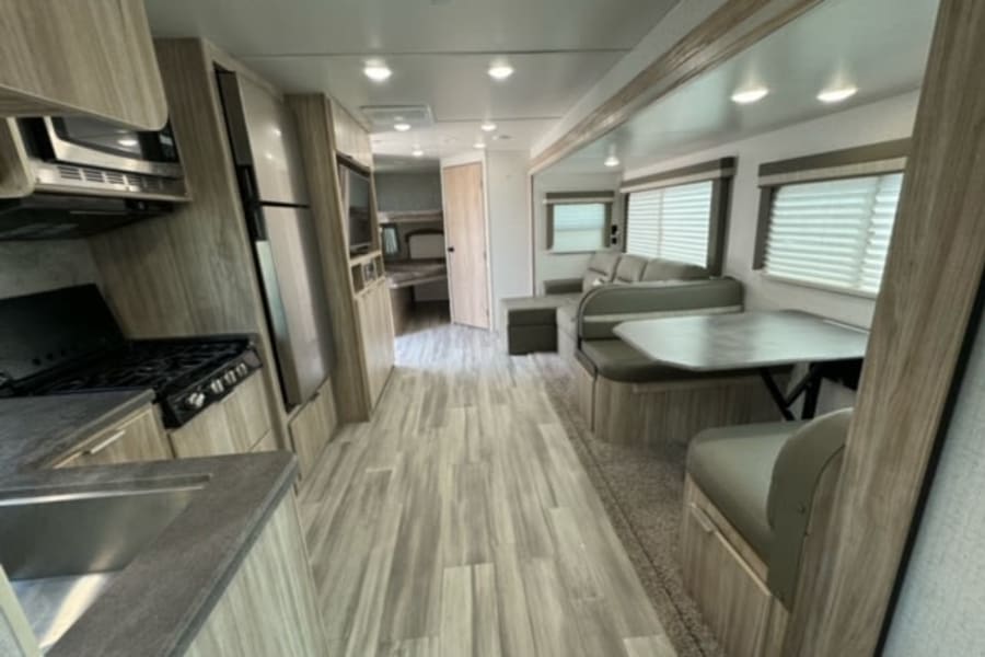 Spacious RV rental interior featuring a full kitchen, dining booth, and living area, perfect for travel accommodation.