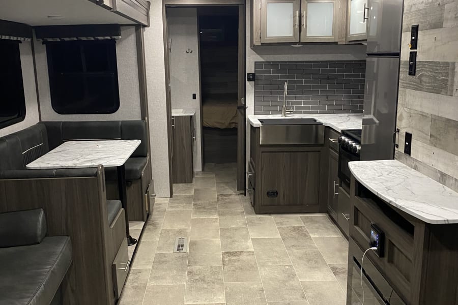 Modern RV rental interior with a cozy dinette, well-equipped kitchen, and built-in entertainment, ideal for your next trip.