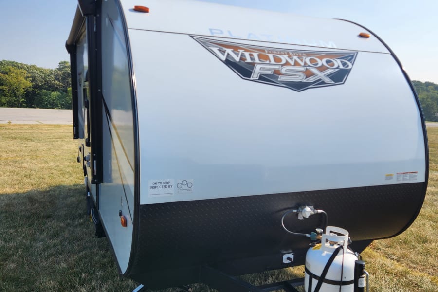 This white and black Forest River Wildwood FSX travel trailer (RV rental) is set up on grass, perfect for your next camping adventure.