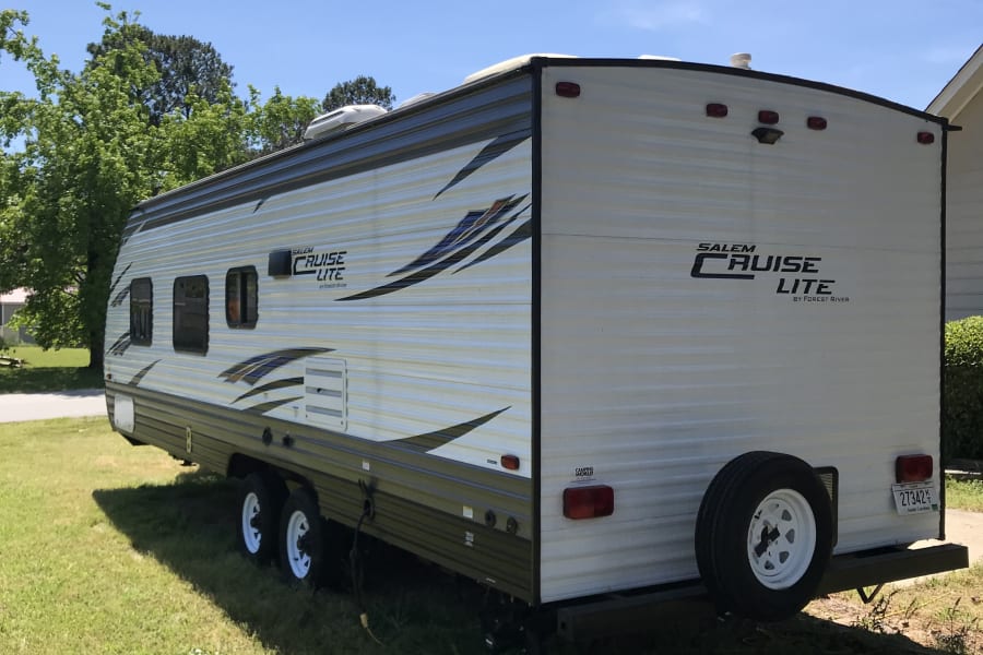 A white Salem Cruise Lite travel trailer, likely an RV rental, parked on green grass under a blue sky.