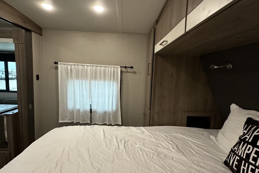 Relax in this RV rental's cozy bedroom. Enjoy the comfy bed, overhead storage, and natural light from the window and skylight.
