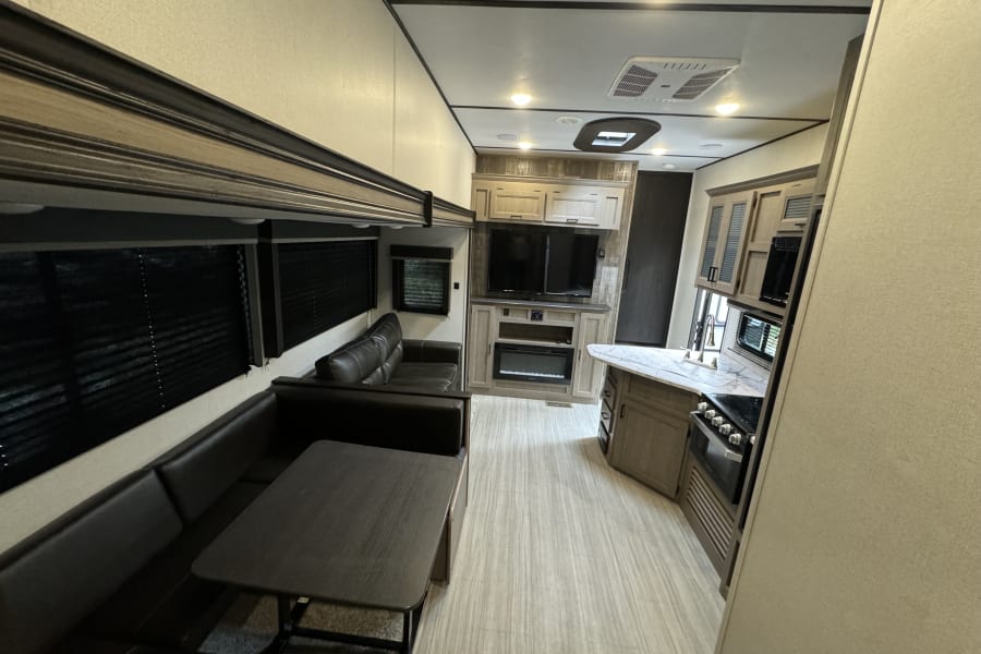 Spacious RV rental interior featuring a modern kitchen, comfortable living area with a sofa, and dining booth.
