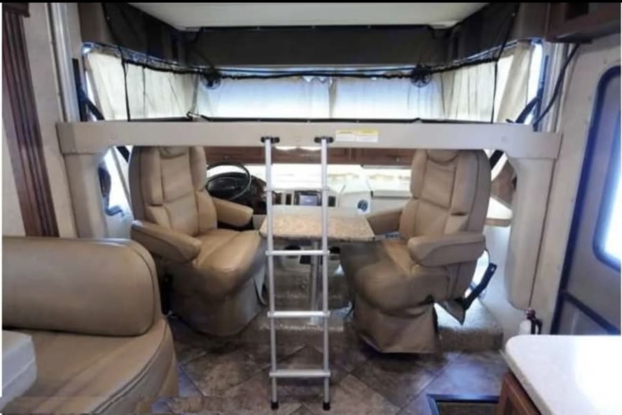 RV rental interior: Front cabin with swiveling seats, a removable table, and an overhead bunk accessible by ladder.