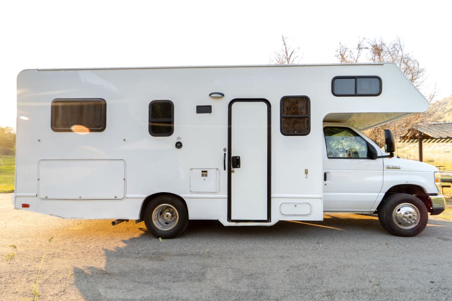 White Ford E-350 RV rental parked at a sunny campsite, ready for your next travel adventure.
