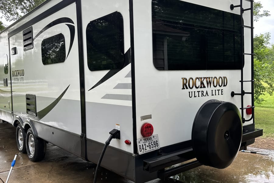 White Rockwood Ultra Lite travel trailer, a potential RV rental, being washed outdoors on a concrete pad.