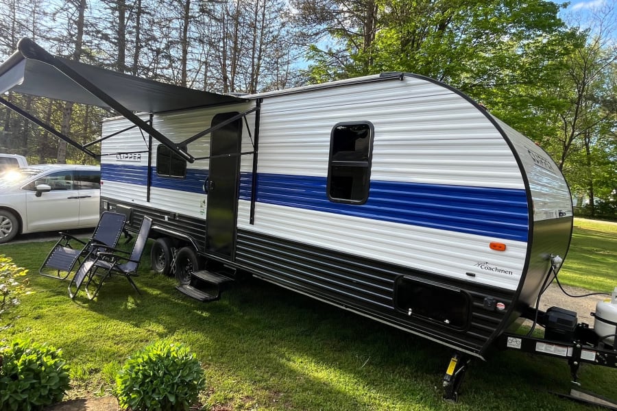 White & blue Clipper rv rental, a travel trailer with an extended awning and chairs, ready for your outdoor adventure.