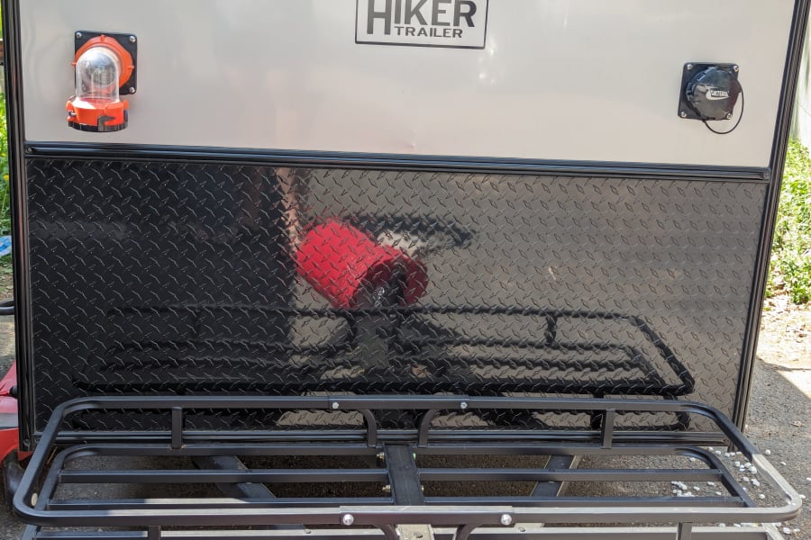 Back of a Hiker Trailer RV rental, featuring utility hookups, durable diamond plate, and a rear cargo rack.