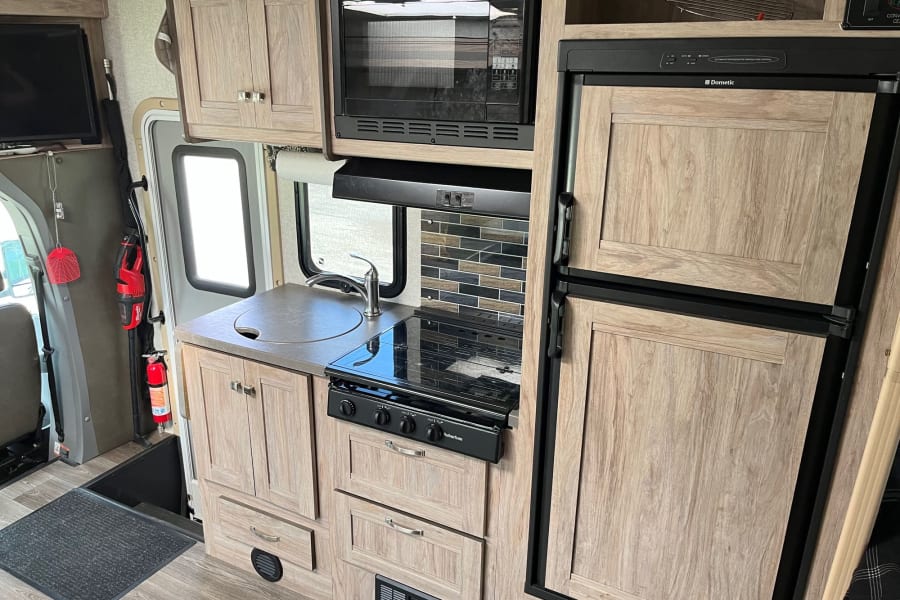 Kitchen includes: fridge, freezer, 3 burner stove top, microwave/convection oven, deep basin sink, upper and lower cabinet storage.