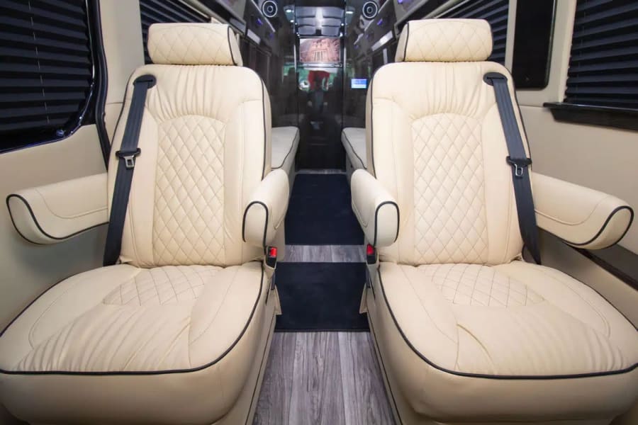 Luxury RV rental interior: plush cream captain's chairs with diamond stitching, black piping, and armrests, designed for comfortable travel.