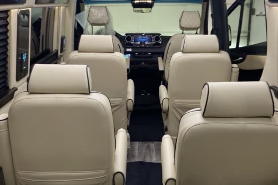 Luxurious RV rental interior features cream leather seats, wood floor, and ambient lighting for a premium travel experience.