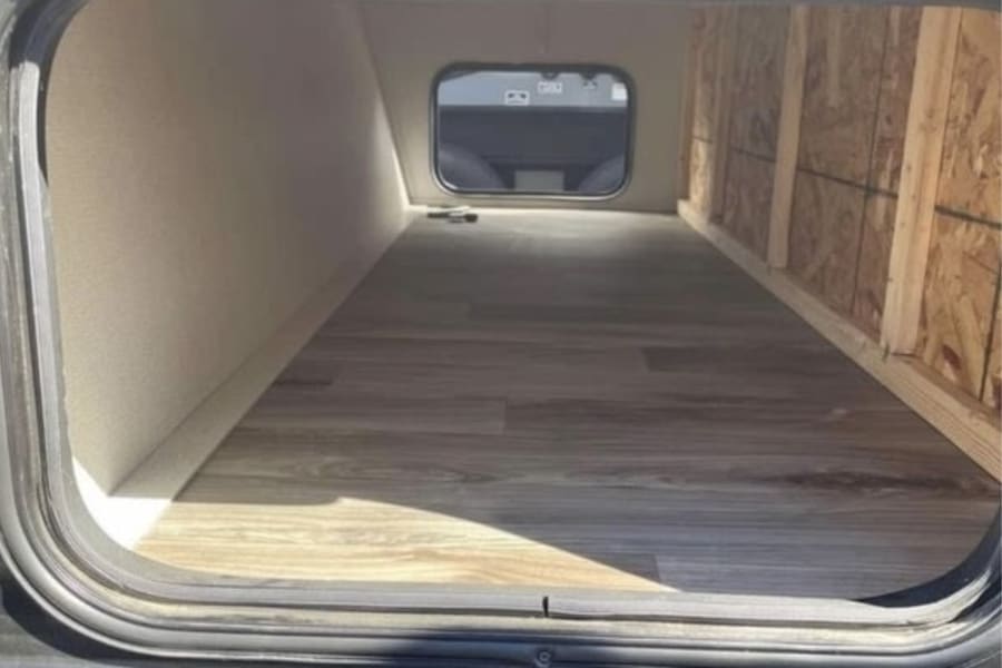 Spacious RV rental pass-through storage bay with wood flooring and unfinished wall. Ideal for stowing gear.