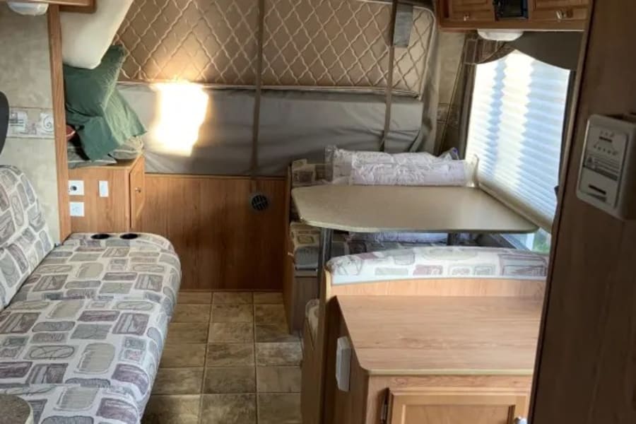 Spacious RV rental interior featuring a comfortable dinette, sofa seating, and a loft bed area.