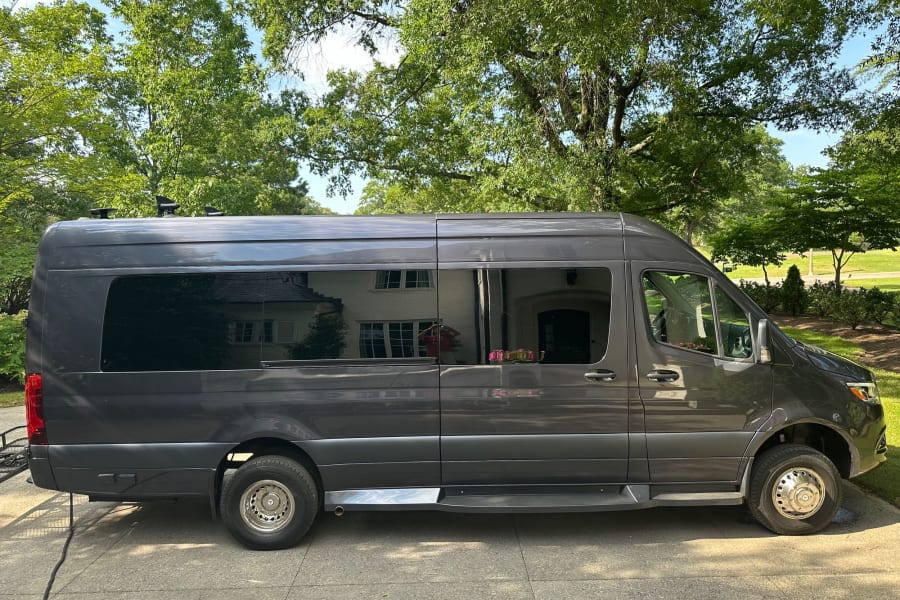 This dark gray Mercedes Sprinter custom van, perfect for rv rental, boasts tinted windows, side steps, and roof vents.