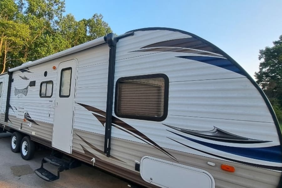 Spacious travel trailer RV rental with an awning and multiple doors, perfect for your next road trip.