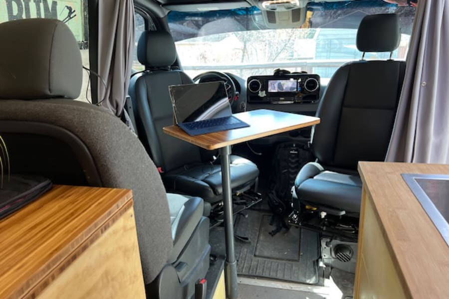 This **rv rental** shows a clever **van conversion** with a laptop desk between the front seats, perfect for **mobile work**.