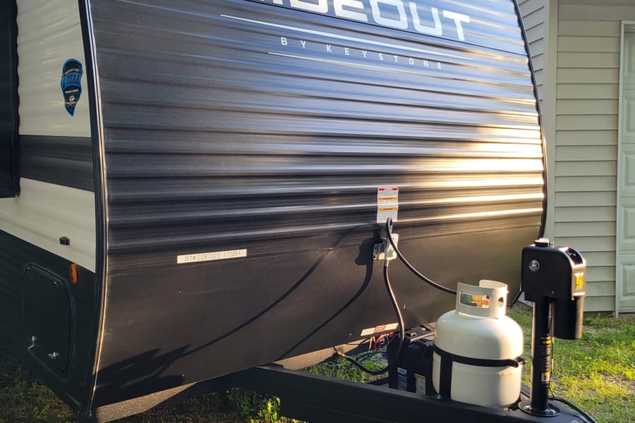 This sleek black and white Hideout by Keystone travel trailer, ideal for an RV rental, is parked and ready.