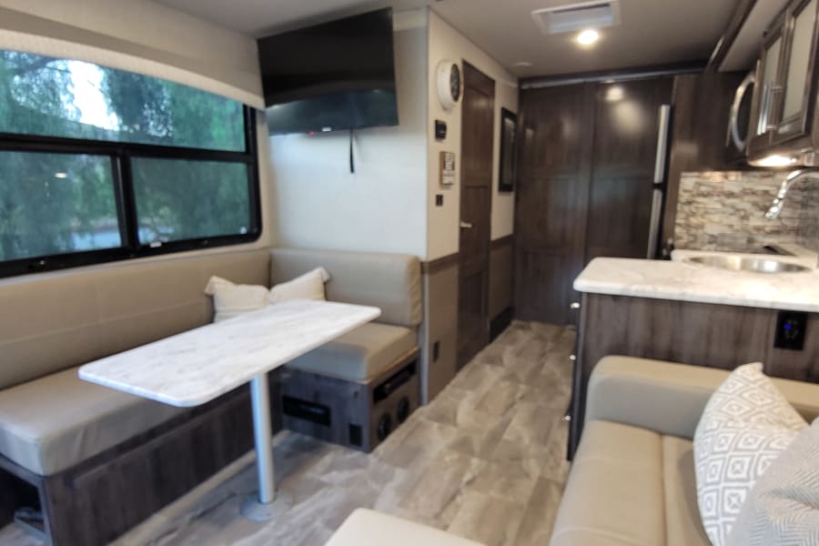 Spacious and modern RV rental interior featuring a dinette, kitchen, and living area for comfortable travel.