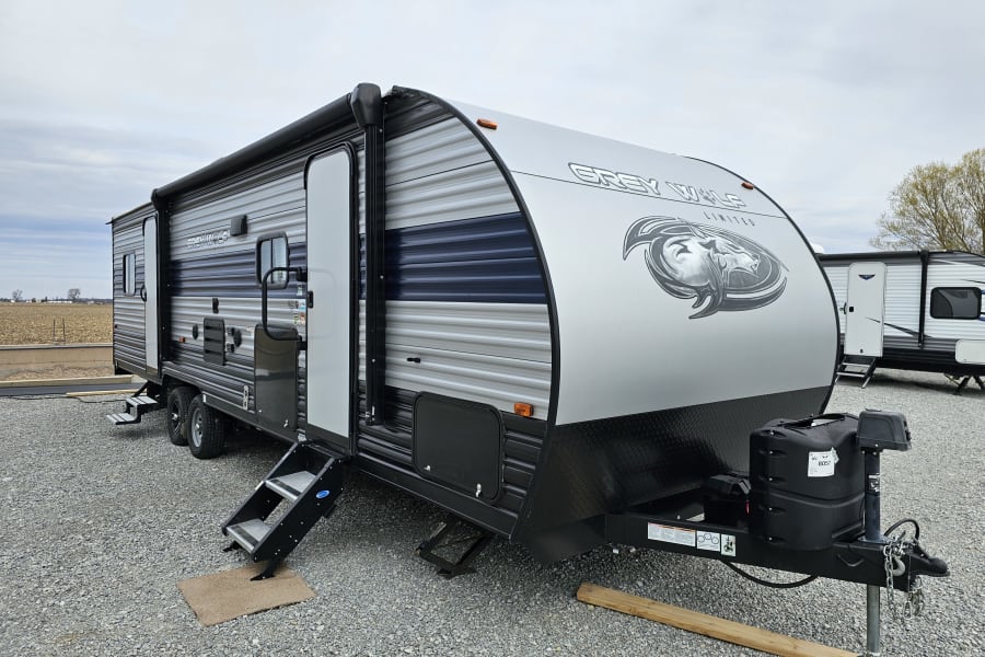 Explore the outdoors with this Grey Wolf Limited travel trailer RV rental, ready on a gravel lot.
