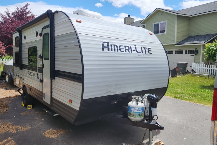 RV rental: An Ameri-Lite travel trailer parked on a residential driveway. Ready for its next adventure!