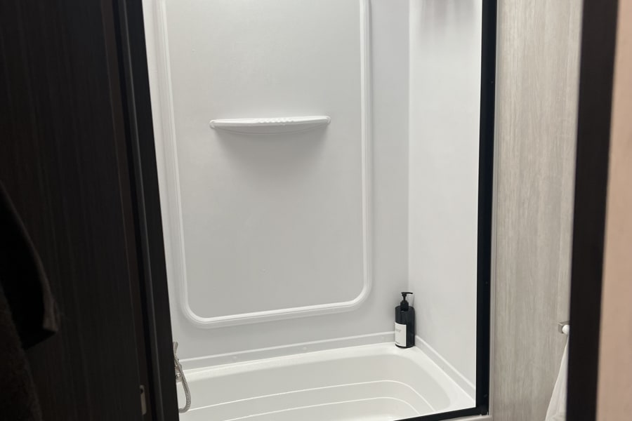 Experience comfort in a compact rv rental bathroom, featuring a clean shower/tub combo, toilet, and essential toiletries.