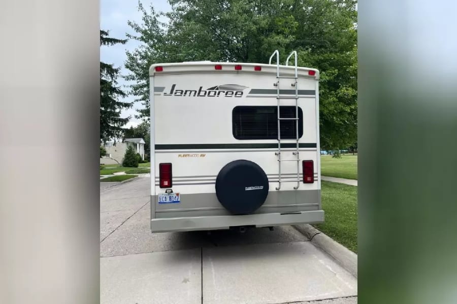 A white Fleetwood Jamboree RV, shown from the rear with a ladder and spare tire, ideal for **rv rental** journeys.