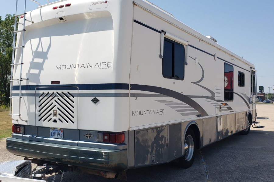 Large white Mountain Aire RV (Newmar) with a rear ladder and Kansas plate, ready for an RV rental trip.