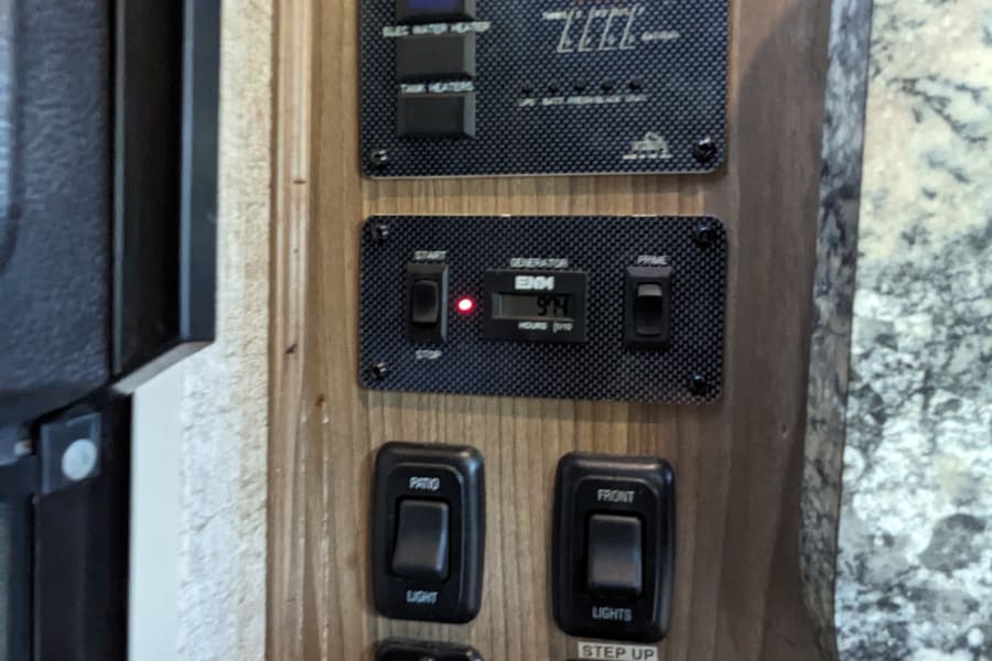 RV rental control panel showing generator (974 hrs), water heaters, tank heaters, interior/patio lights, and step controls.