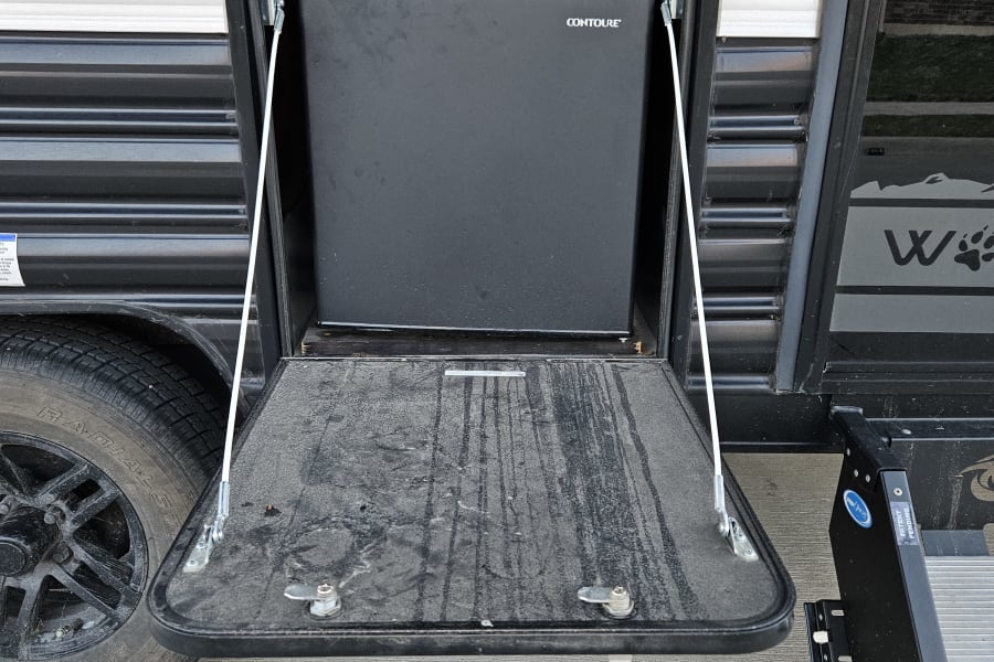 This RV rental features an exterior compartment with a Contoure fridge & pull-down table, perfect for an outdoor kitchen setup.