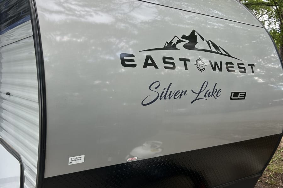 Front view of an "EAST TO WEST Silver Lake LE" travel trailer, perfect for an rv rental or camping trip. Propane & battery visible.