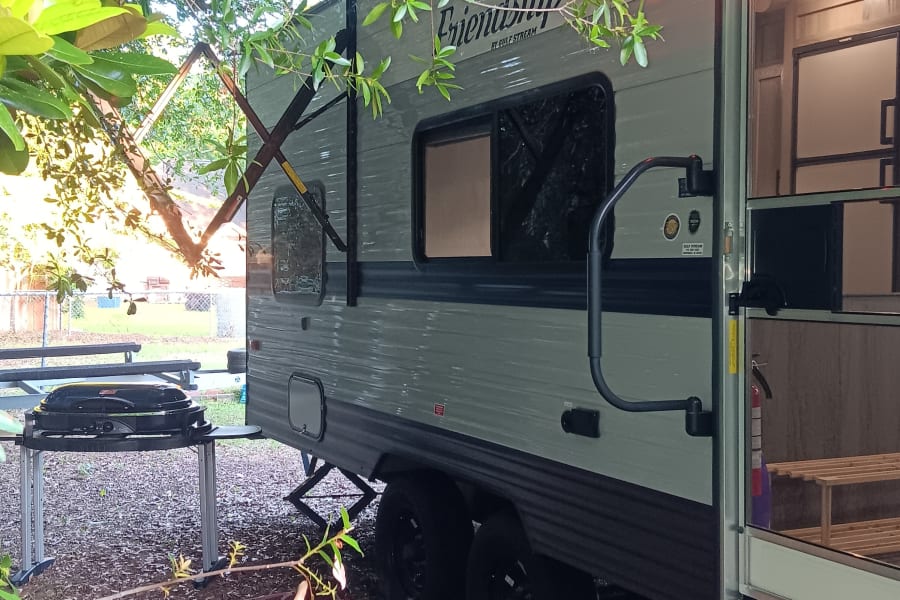 Relaxing RV rental setup with extended awning, outdoor rug, and grill. Perfect for a cozy outdoor retreat.