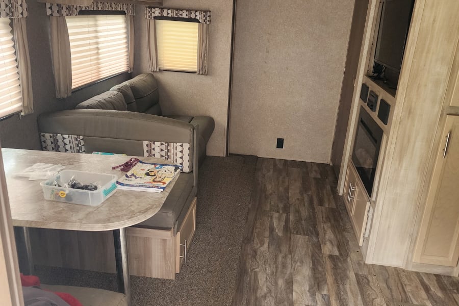 RV rental interior: a versatile living space with a convertible dinette, ample storage, and modern entertainment amenities.