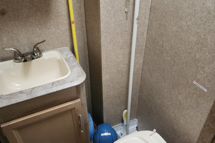 This RV rental's small bathroom features a sink, toilet, and specific instructions for toilet paper disposal.