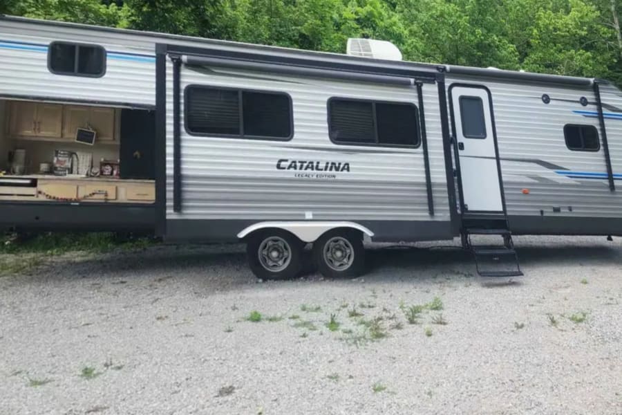 Experience adventure with this Catalina Legacy Edition RV rental, a silver travel trailer featuring an open outdoor kitchen slide-out.