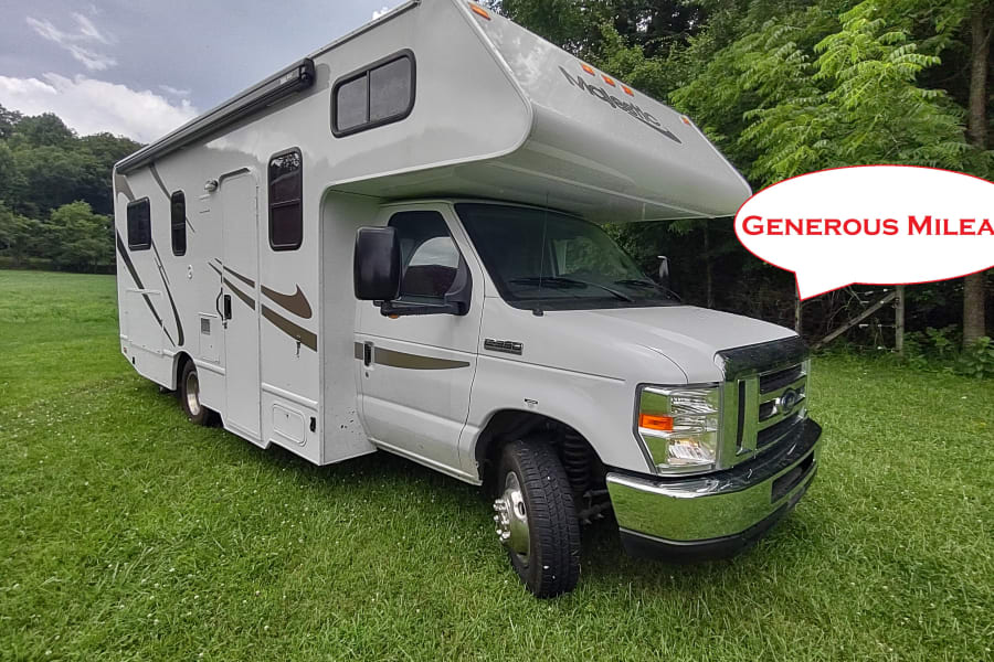 White RV rental motorhome on green grass, backed by trees. A speech bubble states 'GENEROUS MILEAGE'. Ready for your travels!