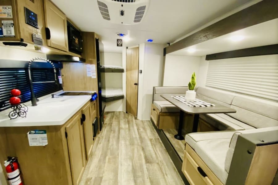 Modern RV rental interior: a bright kitchen with sink, cozy U-shaped dinette, and bunk beds. Perfect for your travels.