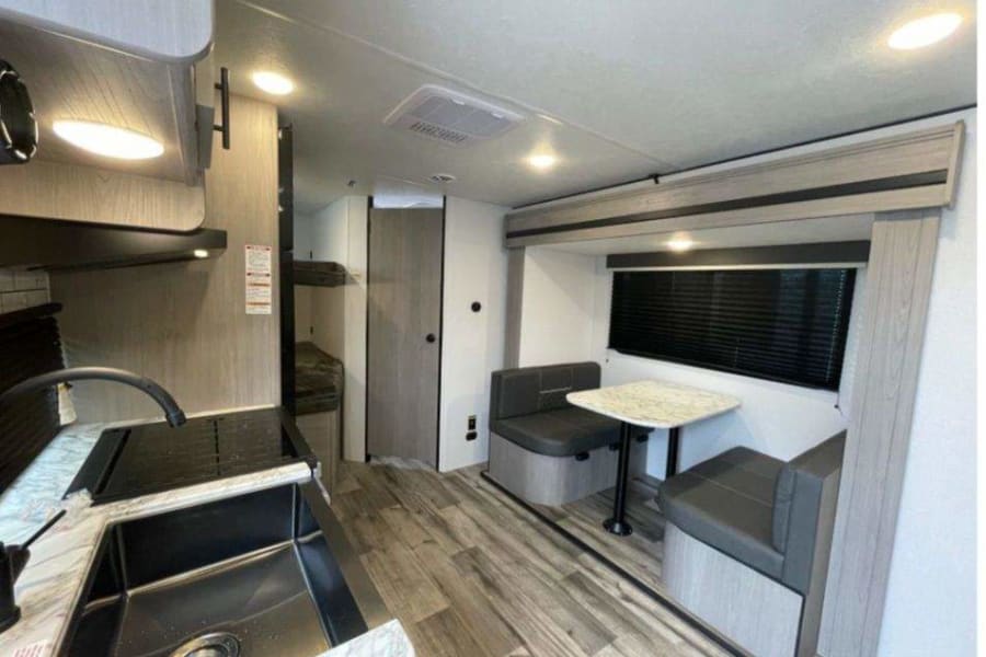 Step inside this cozy rv rental, showcasing a functional kitchen, comfortable dinette, and convenient bunk beds.