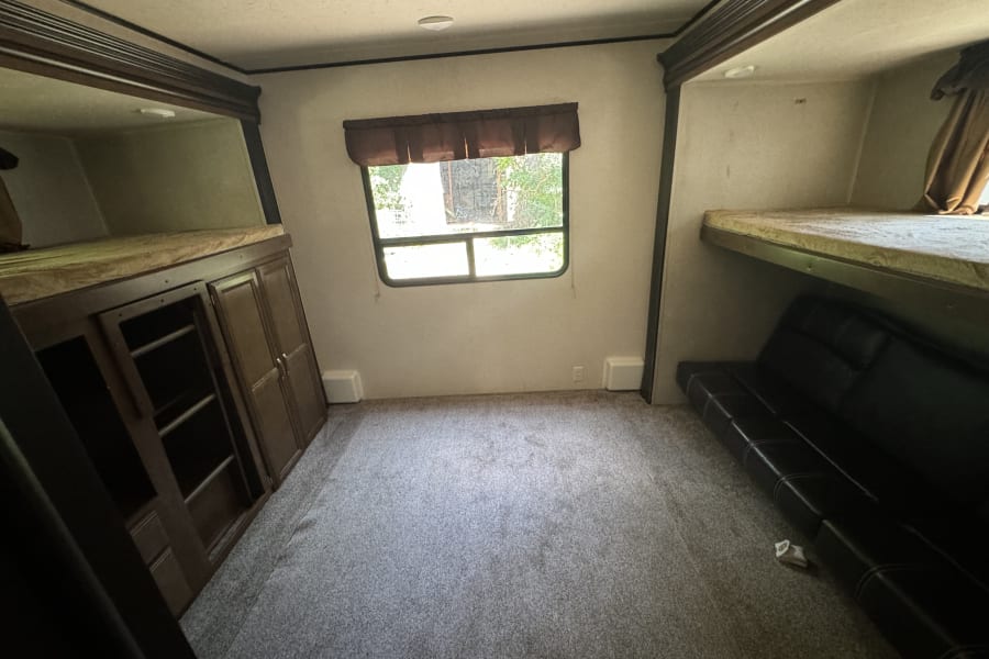 RV rental bunkhouse: spacious interior with bunk beds, sofa, and storage cabinets for comfortable travel.