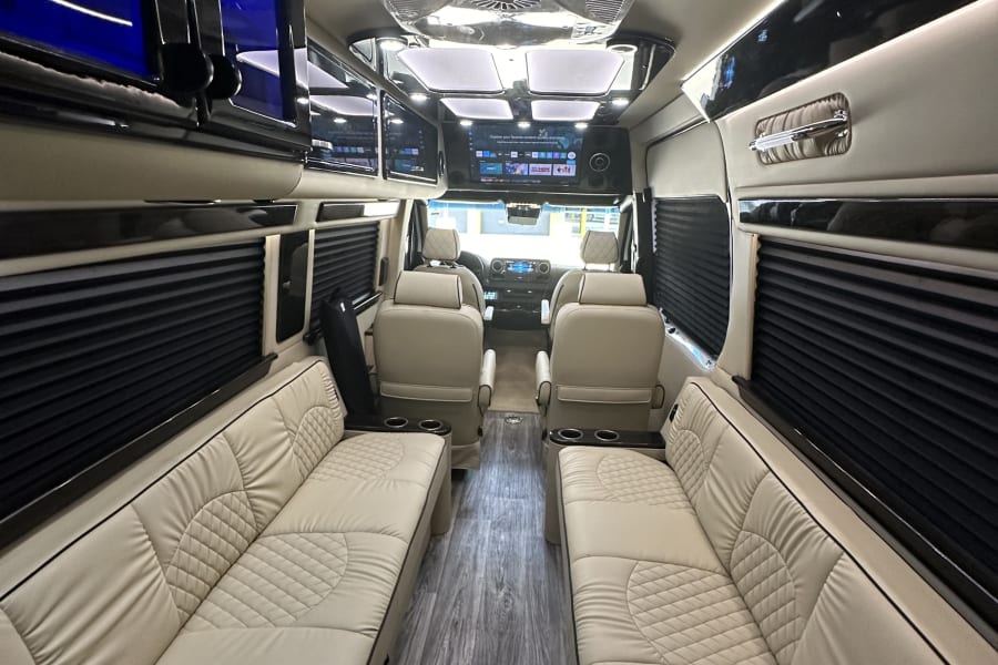 Experience a luxury rv rental! Spacious interior with plush cream seating, wood floors, and modern amenities.