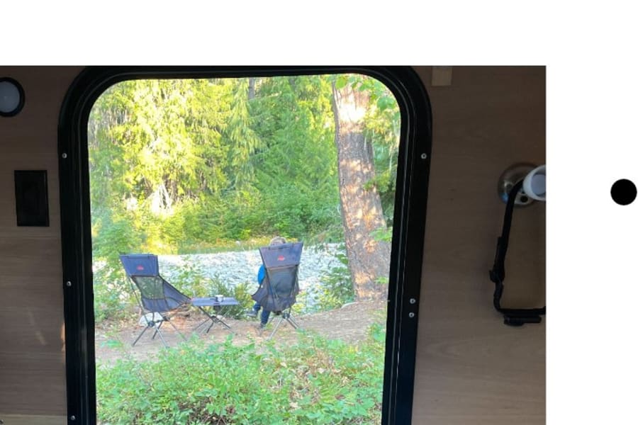 Enjoying the riverside view from our RV rental! Camping chairs are set up for a relaxing day in nature.