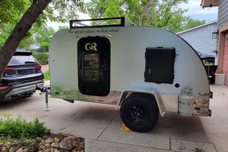 This compact teardrop camper, an ideal RV rental, sits ready for adventure, hitched to an SUV.