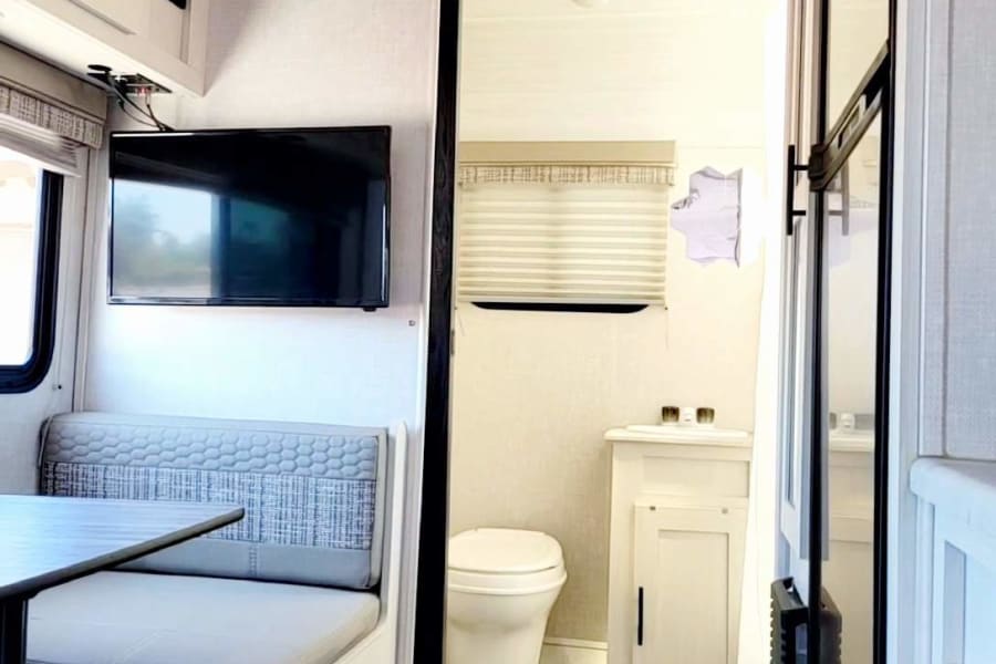 Comfortable RV rental interior featuring a dinette, TV, and accessible bathroom with toilet and sink.