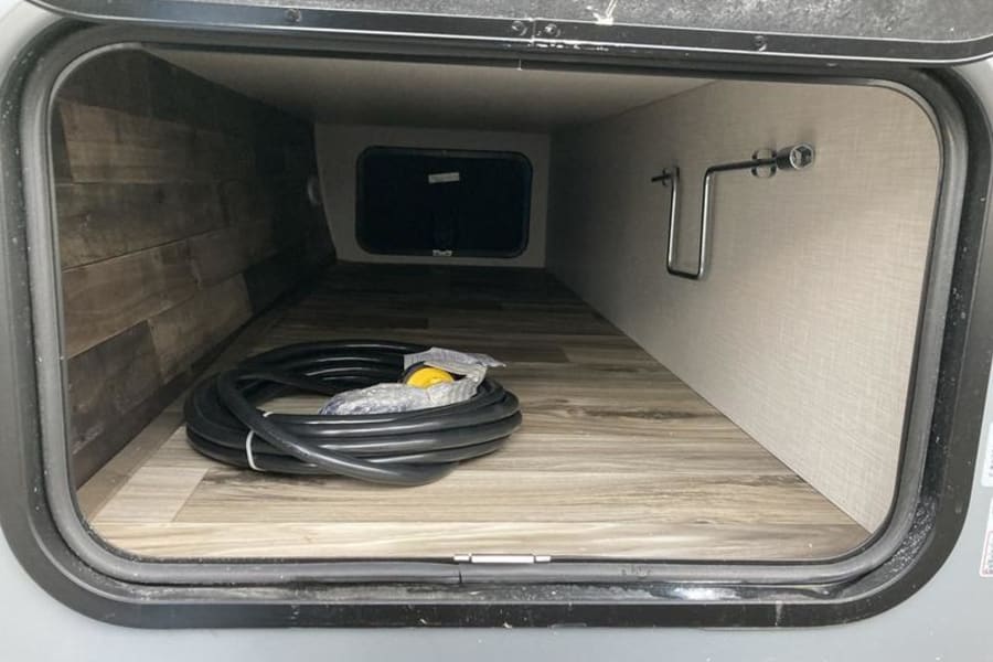 This RV rental's spacious pass-through storage bay, featuring an electrical cord, offers easy access for your essentials.