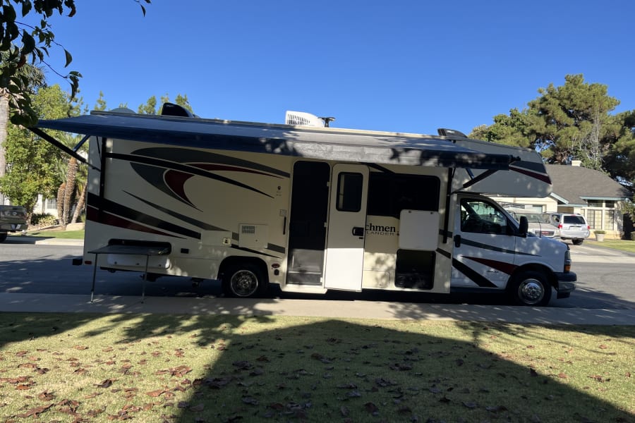 RV rental with an extended awning and outdoor table, set up under a clear sky for a perfect day of outdoor living.