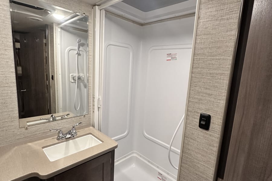 RV rental bathroom: A compact space with a sink, mirror, and shower, designed for comfortable travel.